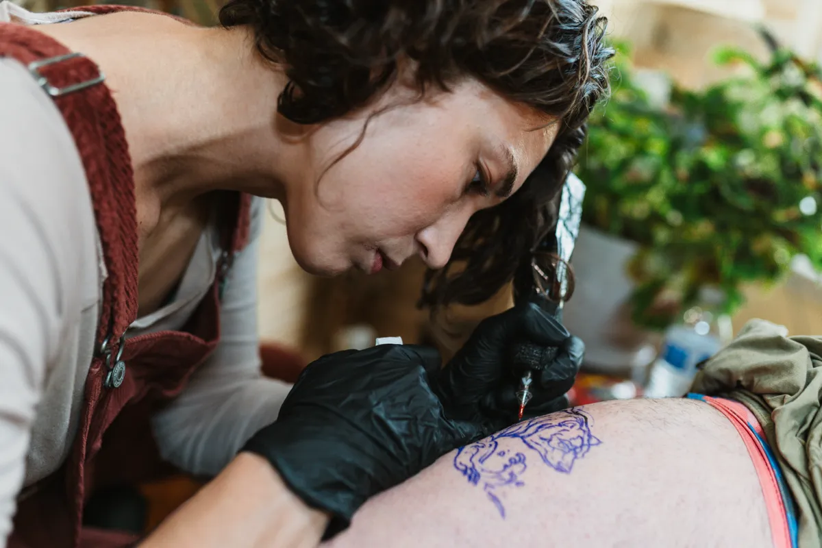 Close view of a tattoo artist outlining a design on a client's skin