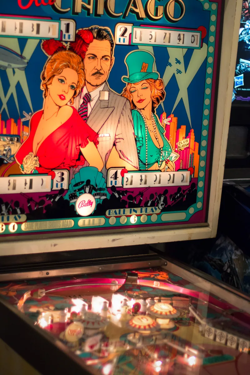The illuminated backglass of a Bally Old Chicago machine above its lit playfield.