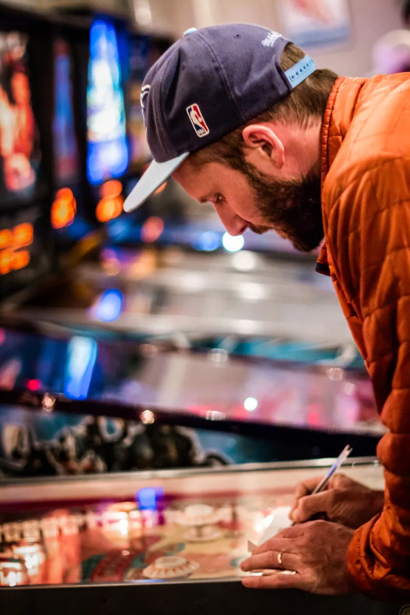 A player bends close to a machine to write down a score.