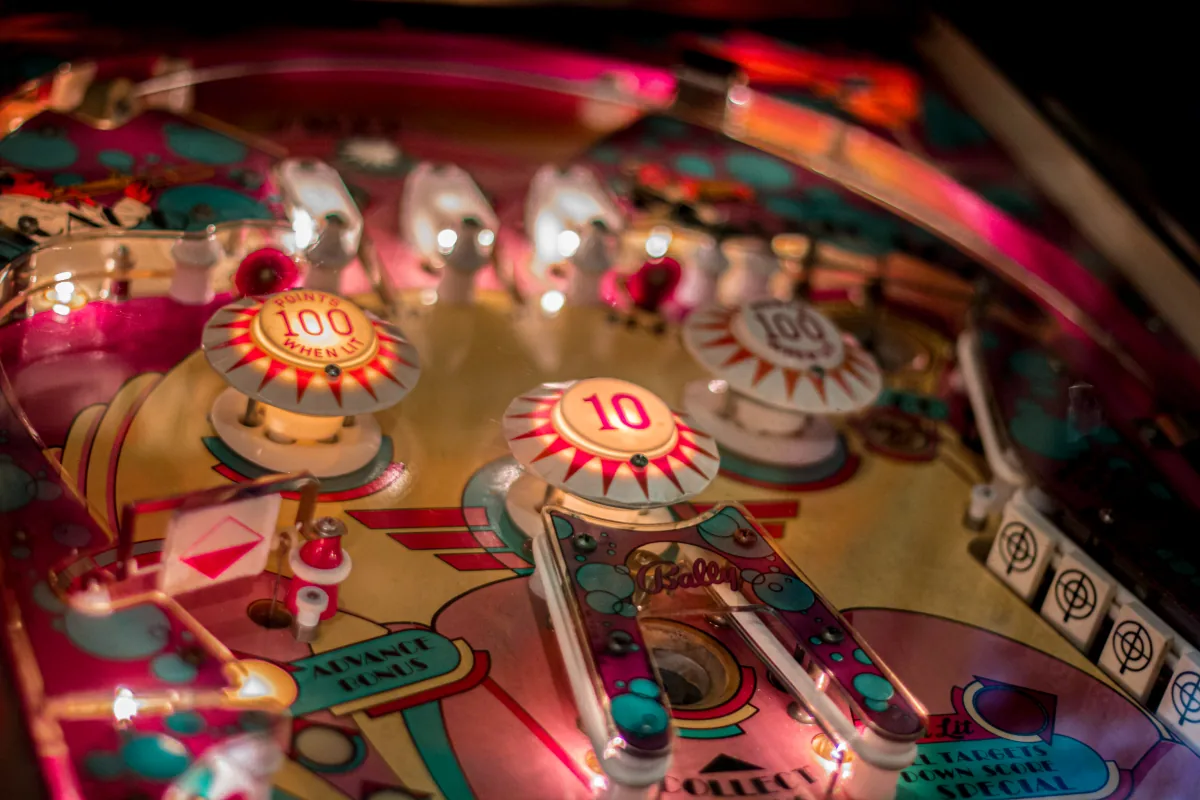 Two lit scoring bumpers stand out against a pink and teal playfield.