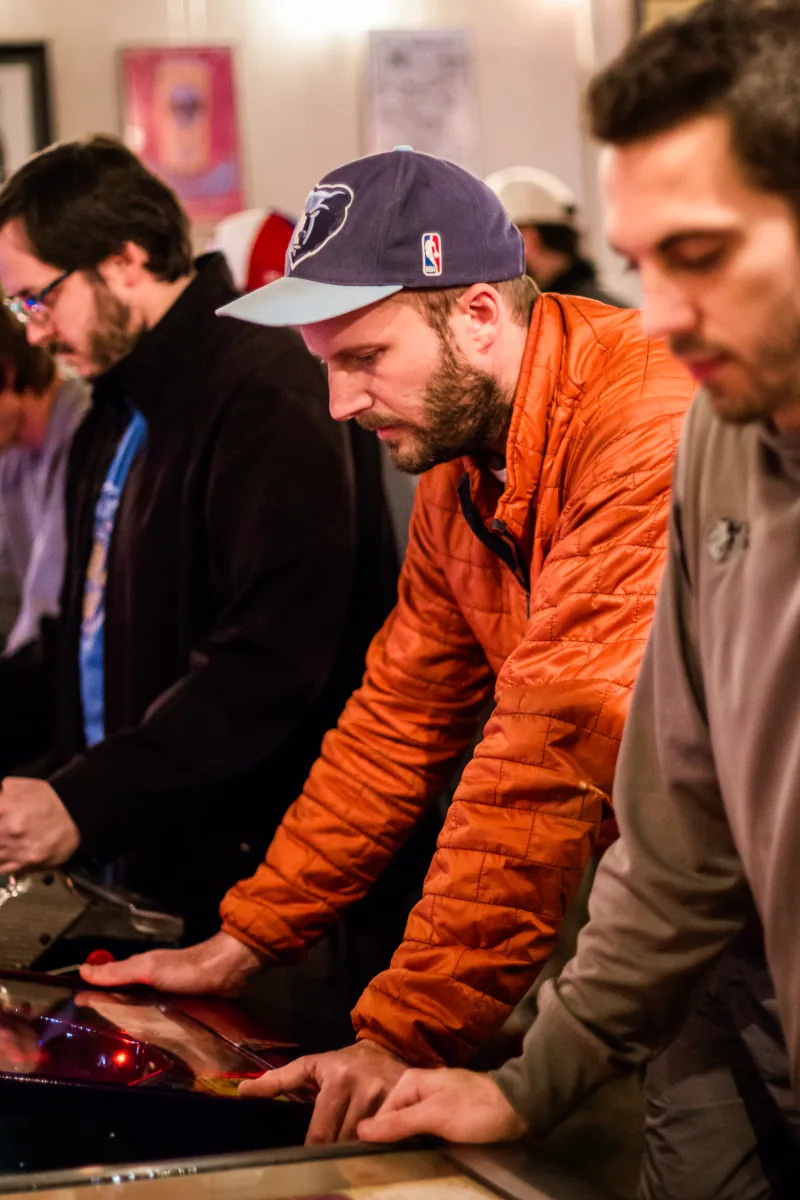 Three players work adjacent machines, their faces lit from below.