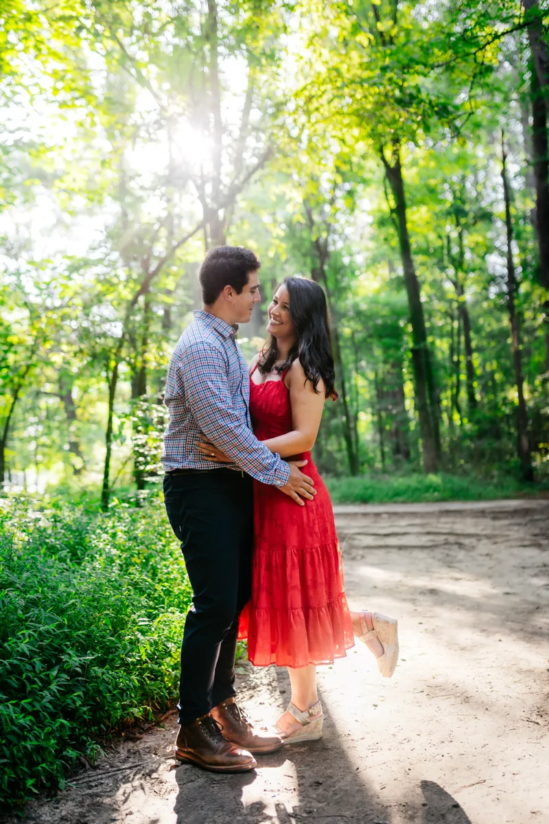 A couple standing close together on a woodland path, backlit by afternoon sun