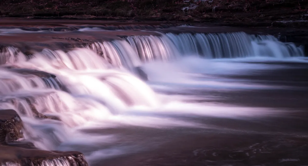 A wide waterfall smoothed into ribbons of white by a long exposure