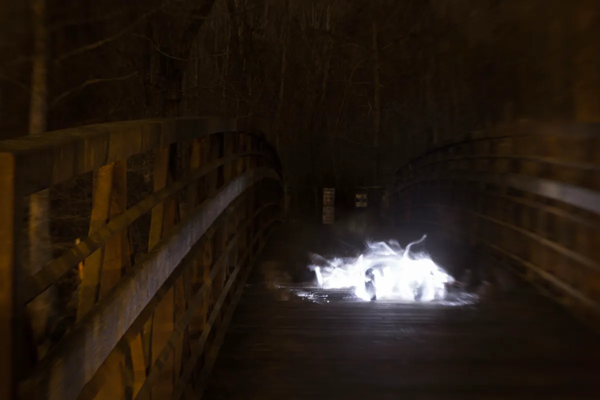 A burst of white light on a dark wooden bridge at night
