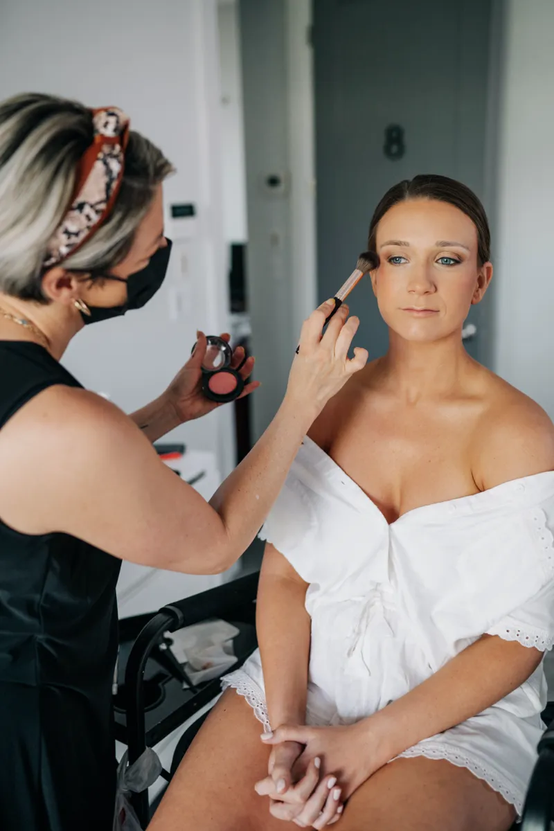 A bride having her makeup applied before the ceremony