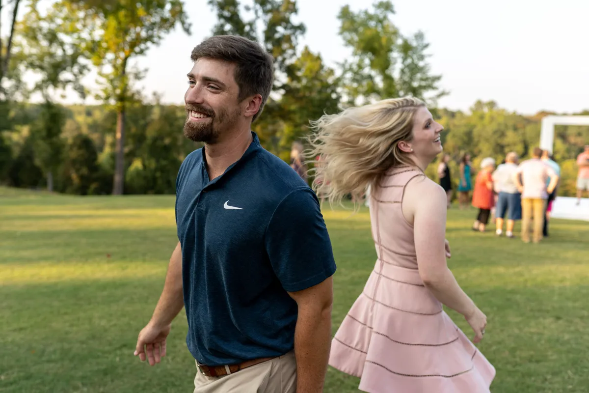 A couple turning to face each other, laughing, at an outdoor celebration